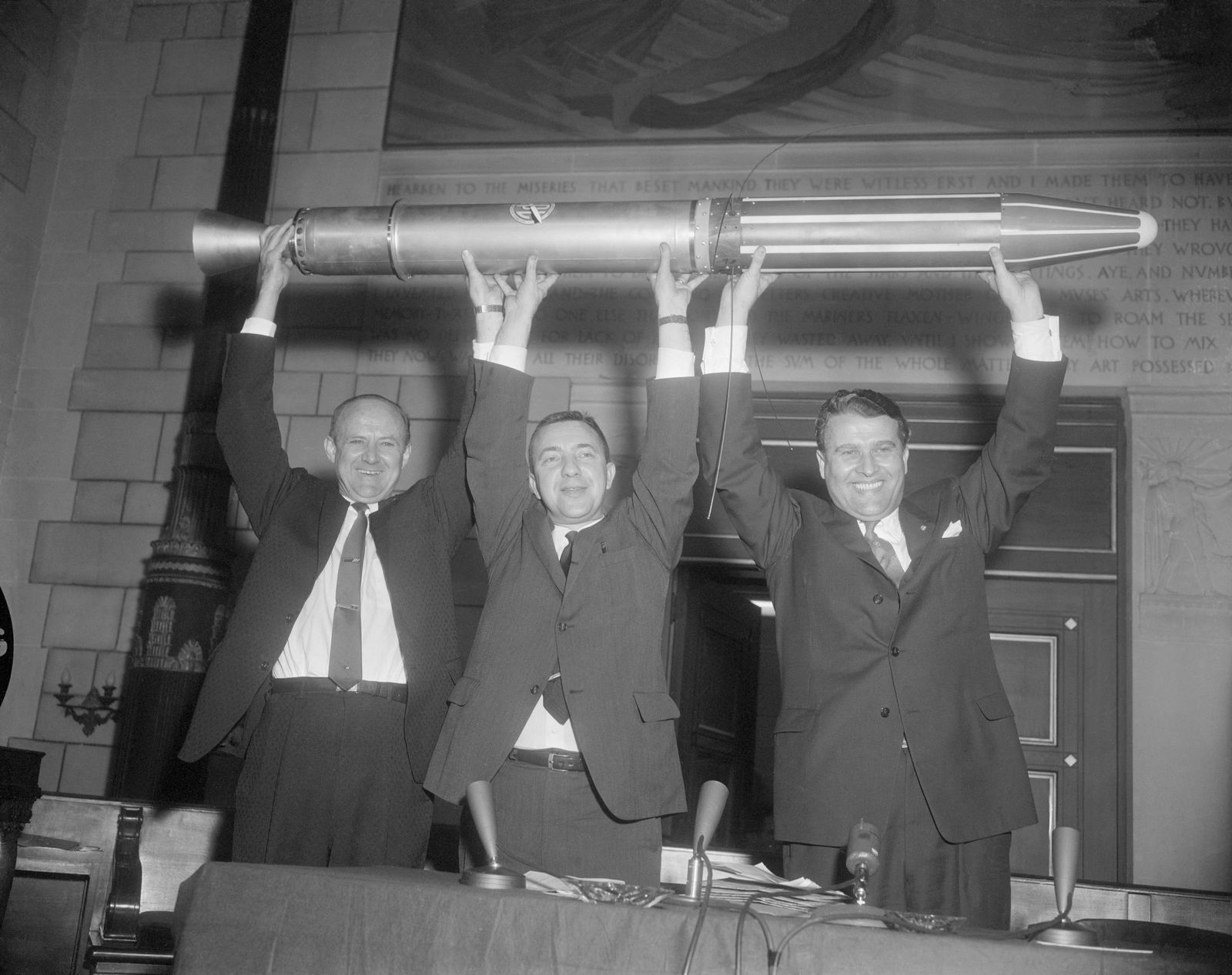 Scientists hold a model of Explorer 1 satellite overhead