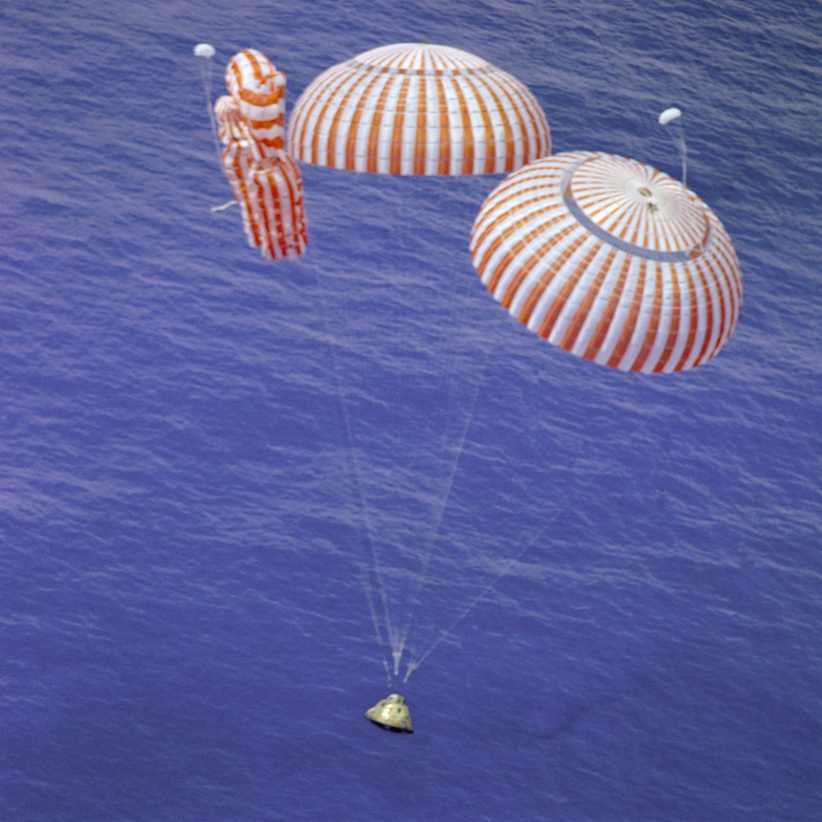An Apollo command module descending under parachutes