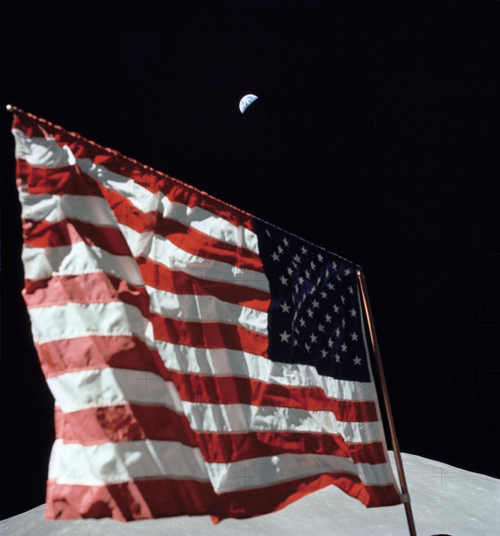 Harrison Schmitt beside the flag with the Earth hanging above